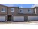 Townhome exterior featuring brick driveways, garages, and covered front porch at 9605 Oliver Hills Ave, Las Vegas, NV 89143