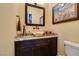 Stylish powder room featuring a vessel sink, decorative mirror, and modern fixtures at 9749 Glistening Brook Ct, Las Vegas, NV 89149