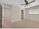 Large carpeted bedroom with a ceiling fan, window, and an open doorway at 11695 Rossovino St, Las Vegas, NV 89183