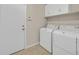 Functional laundry room featuring a washer, dryer, tiled floors, and built-in storage cabinets above for convenience at 11695 Rossovino St, Las Vegas, NV 89183