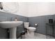 Stylish powder room with gray tile accents, pedestal sink, and decorative mirror adds a touch of elegance at 12844 New Providence St, Las Vegas, NV 89141
