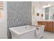 Elegant bathroom featuring a standalone tub, decorative tile wall, and wood vanity with dual sinks at 12844 New Providence St, Las Vegas, NV 89141