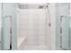 Modern walk-in shower with white tile, glass doors, rainfall showerhead and a built-in bench at 12844 New Providence St, Las Vegas, NV 89141