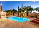 Backyard pool featuring outdoor lighting, green landscaping, and a brick wall at 2547 Serenity Hollow Dr, Henderson, NV 89052
