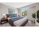 Staged main bedroom with large window, gray bed frame and blue pillows, featuring decor and a side table at 2834 Crystal Lantern Dr, Henderson, NV 89074