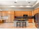 Bright kitchen featuring tile floors, breakfast bar, natural wood cabinets, and modern stainless steel appliances at 4649 Bird View Ct, Las Vegas, NV 89129