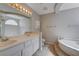 Bright bathroom featuring double sinks, a large mirror, and a separate bathtub and toilet area at 472 Staghorn Pass Ave, Las Vegas, NV 89183