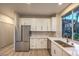 Bright kitchen features stainless steel appliances, white cabinets, and a window with a serene outdoor view at 5010 Crooked Stick Way, Las Vegas, NV 89113
