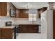 Updated kitchen with stainless steel appliances, herringbone backsplash, dark wooden cabinets, and white tile floors at 6225 Rassler Ave, Las Vegas, NV 89107
