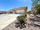 Beige home featuring a large, two-car garage and a concrete driveway with desert landscaping under a bright blue sky at 6287 Stone Hollow Ave, Las Vegas, NV 89156