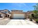 Beige home featuring a large, two-car garage and a concrete driveway with desert landscaping under a bright blue sky at 6287 Stone Hollow Ave, Las Vegas, NV 89156