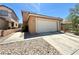 Beige home featuring a large, two-car garage and a concrete driveway with rock landscaping under a bright blue sky at 6287 Stone Hollow Ave, Las Vegas, NV 89156
