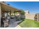 Spacious backyard featuring a covered patio, artificial grass, and a tranquil water feature at 7030 Silver Ridge Peak St, Las Vegas, NV 89166