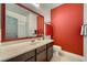Bright bathroom featuring a vanity with a framed mirror and a red accent wall at 7030 Silver Ridge Peak St, Las Vegas, NV 89166