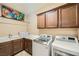 Well-lit laundry room equipped with modern washer and dryer units and ample cabinet space at 7030 Silver Ridge Peak St, Las Vegas, NV 89166