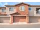 Townhome exterior with a beige and brown facade, featuring three garages and symmetrical windows at 965 Nevada State Dr # 15104, Henderson, NV 89002