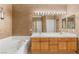 Bathroom featuring a double sink vanity, large mirror, decorative lighting, tile flooring and soaking tub at 9688 Meeks Bay Ave, Las Vegas, NV 89148
