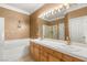 Bathroom featuring a double sink vanity, large mirror, soaking tub and decorative lighting at 9688 Meeks Bay Ave, Las Vegas, NV 89148
