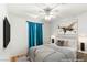 Staged bedroom with a ceiling fan, accent wall, flat screen tv and a side table with lamps at 9688 Meeks Bay Ave, Las Vegas, NV 89148