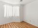 Minimalist bedroom with wood floors, a large window with white curtains, and neutral-colored walls at 9688 Meeks Bay Ave, Las Vegas, NV 89148