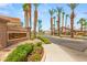 Community entrance with stone signage, lush landscaping, and towering palm trees at 9688 Meeks Bay Ave, Las Vegas, NV 89148