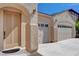 Beige single story home featuring an arched doorway and three car garage under a clear blue sky at 981 Buffalo River Ave, Henderson, NV 89002