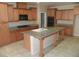 Spacious kitchen with wood cabinets, tile floors, granite countertops, and an island with sink at 981 Buffalo River Ave, Henderson, NV 89002