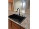 Close-up of a modern kitchen sink with a sleek black faucet and granite countertop, open to the living area at 981 Buffalo River Ave, Henderson, NV 89002