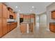 An open-concept kitchen features wood cabinets, granite countertops, a center island, and tiled floors at 981 Buffalo River Ave, Henderson, NV 89002