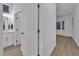 Bright hallway with light wood flooring, white walls, and view of a bathroom with white vanity at 10801 Clarion Ln, Las Vegas, NV 89134