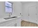 Bright laundry room featuring a modern sink, white cabinets, and a convenient exterior door at 10801 Clarion Ln, Las Vegas, NV 89134