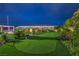 Backyard putting green and outdoor living space with adjacent patio, landscaping, and lighting at 11238 Rebel Dome Ct, Las Vegas, NV 89141