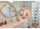 Stylish bathroom featuring double sinks, decorative mirrors, and leafy wallpaper, creating a modern and refreshing space at 11238 Rebel Dome Ct, Las Vegas, NV 89141