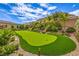 Beautiful backyard putting green surrounded by lush landscaping in a luxury property at 11238 Rebel Dome Ct, Las Vegas, NV 89141