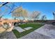 Landscaped backyard with synthetic grass, desert landscaping, and a cozy seating area offers a private retreat at 1610 Dire Wolf Avenue, North Las Vegas, NV 89084