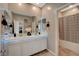 Bathroom with double sink vanity, decorative mirror lighting, and tiled shower at 1610 Dire Wolf Avenue, North Las Vegas, NV 89084