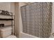 Bright bathroom featuring a decorative shower curtain, toilet and black metal shelving unit at 1610 Dire Wolf Avenue, North Las Vegas, NV 89084