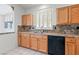 Kitchen showcasing wooden cabinetry, a black dishwasher, stainless steel sink and granite countertops at 1904 Bellview St, Las Vegas, NV 89134