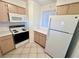 Compact kitchen featuring light wood cabinets, white appliances and tile flooring at 2064 Mesquite Ln # 102, Laughlin, NV 89029