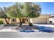 Charming single-story home featuring a desert landscape, mature trees, and an attached two-car garage at 2183 Waterton Rivers Dr, Henderson, NV 89044