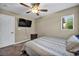 A comfortable bedroom has a mounted TV, ceiling fan, and a bedside table next to the bed at 3232 Brayton Mist Dr, North Las Vegas, NV 89081