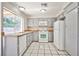 A well-lit kitchen with gray cabinets, white appliances, a window, and tile floors at 3596 Bronco Rd, Las Vegas, NV 89103