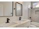 Modern bathroom featuring dual sinks with black fixtures and a tub-shower with gray tile at 4010 Herblinda Ln, North Las Vegas, NV 89032