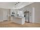Modern kitchen with white cabinets, stainless appliances, island, and stylish pendant lights over sleek wood flooring at 4010 Herblinda Ln, North Las Vegas, NV 89032