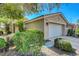 Tan home with a two-car garage is complemented by desert landscaping with mature trees at 4802 Regalo Bello St, Las Vegas, NV 89135