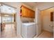 Functional laundry room with washer, dryer, cabinets, and adjacent half bath at 5450 Grain Mill Rd, Pahrump, NV 89061