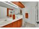 Modern bathroom with double sinks, bright lighting, tiled floors, white walls, and orange accents at 605 Devonhall St # 202, Las Vegas, NV 89145