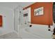 Bright bathroom featuring a soaking tub, a glass-enclosed shower, and orange accent wall at 605 Devonhall St # 202, Las Vegas, NV 89145