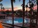Community pool surrounded by palm trees and lounge chairs, reflecting a vibrant sunset sky at 605 Devonhall St # 202, Las Vegas, NV 89145