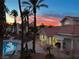 Scenic sunset view of the community pool, poolside cabana, surrounding palm trees, and building architecture at 605 Devonhall St # 202, Las Vegas, NV 89145